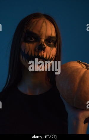 Una ragazza in un uomo morto con la maschera di una zucca su uno sfondo scuro. Halloween Foto Stock