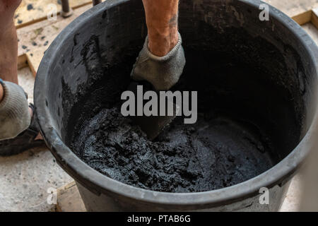 Mans tenere in mano una cazzuola e cemento mescolato nella benna. Foto Stock