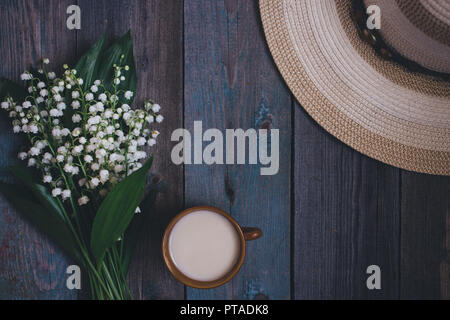 Il giglio della valle bouquet, tazza di caffè, tè, latte, su sfondo di legno Foto Stock