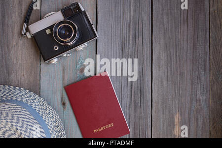 Un passaporto, una fotocamera vintage, un cappello su sfondo di legno Foto Stock