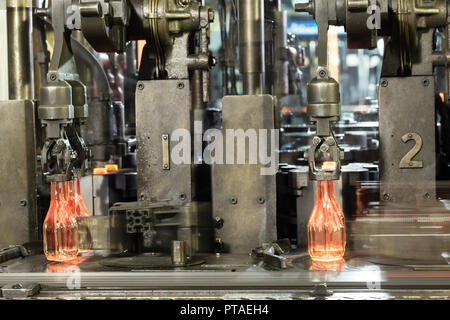 Il caldo di bottiglie di vetro sul trasportatore sono realizzati dal fabbricante di vetro. Caldo rosso bottiglie avanzano lungo il trasportatore in fabbrica Foto Stock