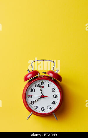 Red vintage sveglia su sfondo giallo. Orologio sveglia con posto per il testo. Si torna a scuola concetto. Foto Stock