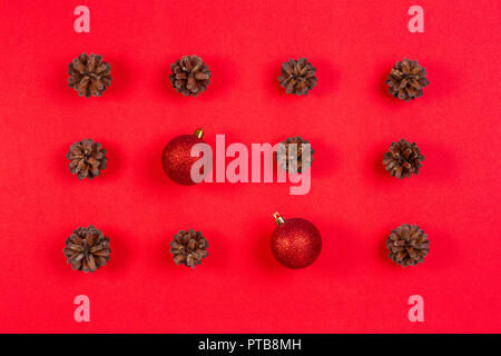 Composizione di natale. Modello realizzato di pigne e rosso decorazione di Natale palle su sfondo rosso. Vista superiore, laici piatta Foto Stock
