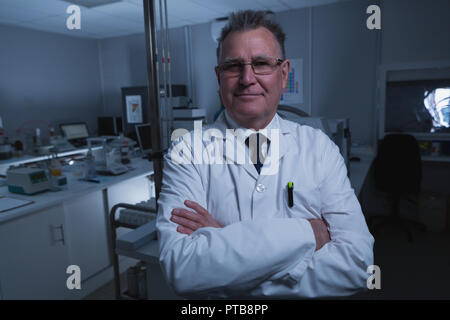 Scienziato maschio in piedi con le braccia incrociate in laboratorio Foto Stock