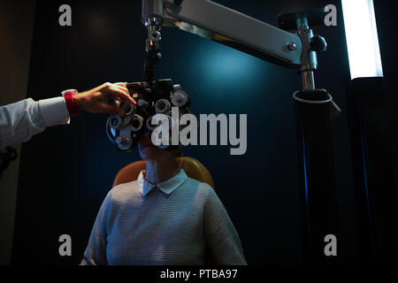 All'ottico optometrista esaminando gli occhi del paziente con phoropter Foto Stock