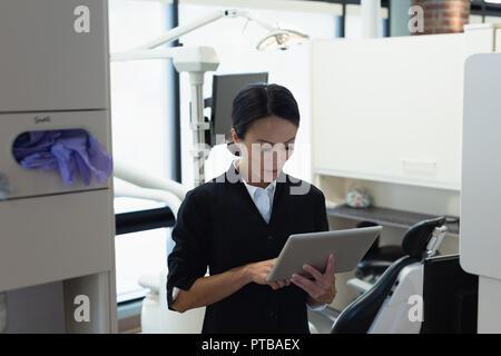 Dentista femmina con tavoletta digitale in clinica dentale Foto Stock