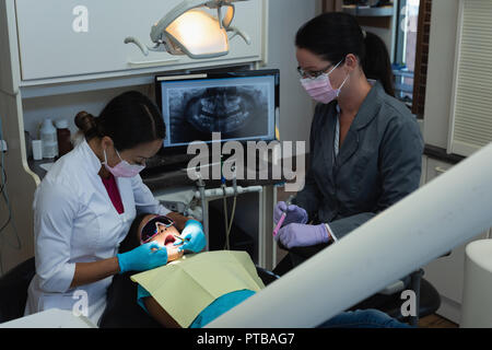 Dentista femmina e infermiere esame paziente con strumenti Foto Stock