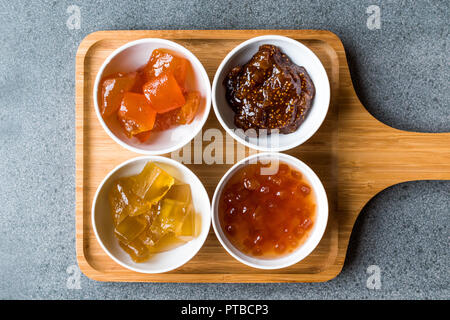 Varie coppa in ceramica di confetture di frutta Fig, mela cotogna, bergamotto, Citrus anguria nel vassoio in legno / Marmellata di arance. Alimenti biologici. Foto Stock