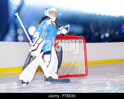 Ritratto di ragazza adolescente goaltender in equipaggiamento protettivo in piedi accanto al netto a hockey Foto Stock