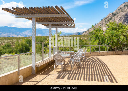 Area attrezzata con tavoli e sedie in ombra del baldacchino con vista mounain sfondo Foto Stock