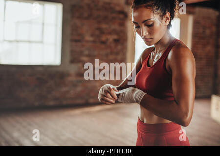 Giovani e sani boxer femmina cinturino da indossare sul polso. Costruito muscolare donna ottenere pronto per l'esercizio di inscatolamento al fitness studio. Foto Stock