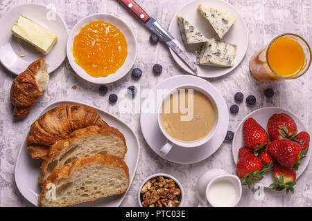 Sana Colazione: caffè con il latte e il latte in una piccola jur, formaggio, succhi di frutta, marmellata, pane, croissant, su sfondo bianco laici piatta Foto Stock