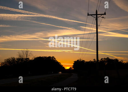 Jet contrails attraversano il cielo al tramonto in North Central Florida. Foto Stock