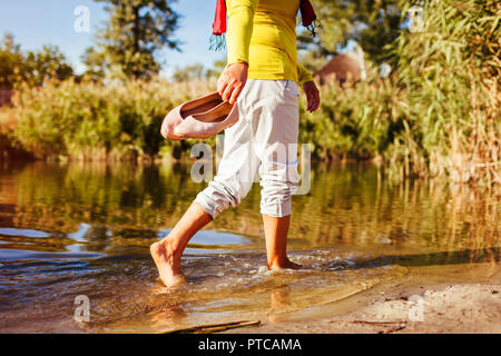 Donna di mezza età camminando sulla riva del fiume sulla giornata d'autunno. Senior lady divertirsi nella foresta e godere la natura. Primo piano Foto Stock