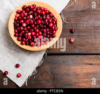 Mature lingonberries rosso in un tondo in legno ciotola, vista dall'alto, spazio vuoto Foto Stock