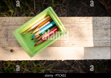 Matite di piccole dimensioni in una scatola e libri Foto Stock