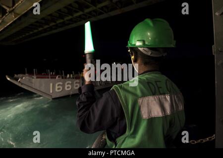 CORAL SEA (12 luglio 2017) Il Marinaio Ebano Anderson, da Atlanta, GA segnali landing craft utility 1666, assegnato alla spiaggia navale unità 7, di discostarsi ben deck di trasporto anfibio USS dock Green Bay (LPD 20) durante un raid anfibio come una parte di talismano Saber 17. Green Bay, parte di un combinato di U.S.-Australia e Nuova Zelanda expeditionary strike gruppo, sta subendo una serie di scenari che aumenterà naval abilità nel funzionamento contro blu-acqua minacce del contraddittorio e nella sua missione primaria di lanciare le forze di marino a terra in marine. Talismano Saber è una biennale U.S.-A Foto Stock