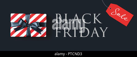 Venerdì nero banner con scatola regalo fasciata in rosso a strisce di carta e legato con la prua nero su sfondo nero, vista dall'alto. Foto Stock