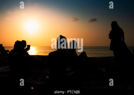 Silhouette di un gruppo di amici appendere fuori sulla spiaggia. Foto Stock