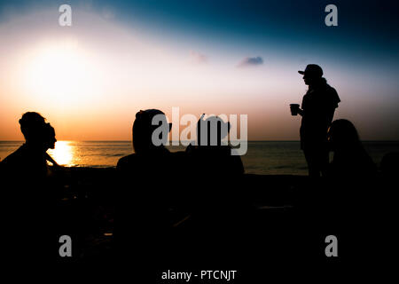Silhouette di un gruppo di amici appendere fuori sulla spiaggia. Foto Stock