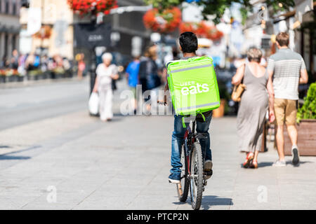 Varsavia, Polonia - Agosto 23, 2018: Uber mangia la bicicletta uomo con segno verde in città vecchia strada storica nella città capitale nel corso estivo soleggiato giorno chiamato Kra Foto Stock