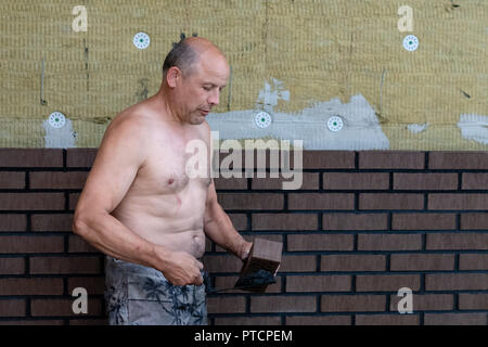 Muratore lavoratore installazione di mattoni su sito in costruzione. Foto Stock