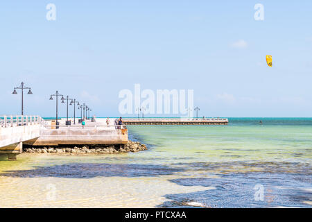 Key West, Stati Uniti d'America - 1 Maggio 2018: la gente che camminava sul jetty pier con un uomo surf, kitesurf con kite sulla scheda in aliscafo in Florida all Oceano Mare, nea Foto Stock