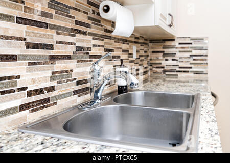 Pulire moderna cucina camera da banco in granito, lavello e rubinetto, armadi in modello di casa in casa o appartamento con asciugamani di carta backsplash decorative Foto Stock