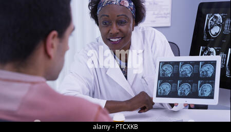 Vista dettagliata del medico donna spiegare ai giovani latino risultati del paziente dal suo MRI Foto Stock