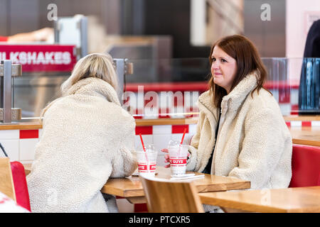 London, Regno Unito - 12 Settembre 2018: Primo piano dei due felici donne seduti a mangiare cinque ragazzi burger ingresso della catena, bere frappè Foto Stock