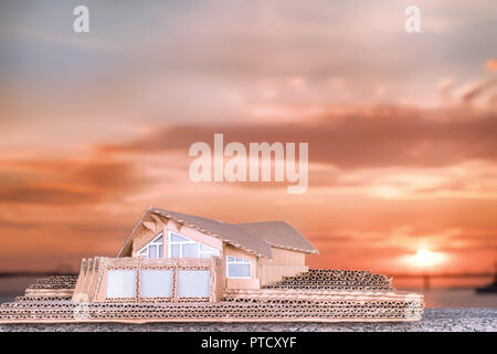 Cottage di lusso modello di cartone contro luminoso Cielo di tramonto Foto Stock