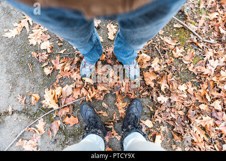 Scarpe, caduto autunno marrone arancione molte foglie sul terreno con donna uomo due giovane piedi piatti lay vista dall'alto verso il basso nei sobborghi di Virginia trekking trail road Foto Stock