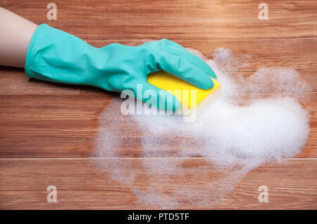 Lavare il pavimento con la mano in guanti con una spugna gialla in schiuma Foto Stock