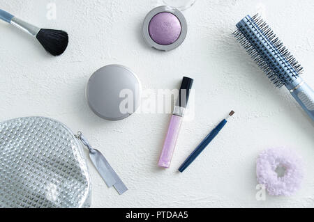 Prodotti cosmetici su un bianco sfondo irregolare, spazzola per il trucco per il viso in polvere, eye shadow lip gloss Pettine capelli sacchetto cosmetico e fascia per capelli Foto Stock