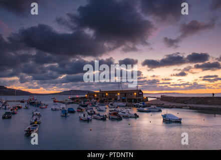 Lyme Regis, Dorset, Regno Unito. Il 9 ottobre 2018. Regno Unito Meteo: Moody mattina nuvole come sunrise colori illuminano il cielo sopra il Cobb, Lyme Regis. Credito: Celia McMahon/Alamy Live News Foto Stock