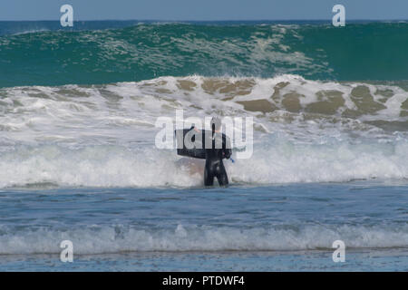 St Ives, Cornwall, Regno Unito. Il 9 ottobre 2018. Regno Unito Meteo. Surfers rendendo la maggior parte del wam e condizioni ventose sulla spiaggia di St Ives questo pomeriggio. Credito: Simon Maycock/Alamy Live News Foto Stock