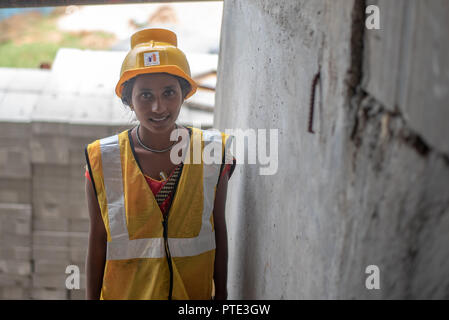Donna operaio con la sicurezza usura alla costruzione sito. Città Urban in India è vedere un sacco di progetti di sviluppo. Foto Stock
