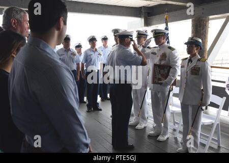 Membri del guardacoste Blackfin presente Lt. Edward Kalankiewicz con la taglierina Blackfin la messa in opera della fiamma all'Blackfin il cambiamento di comando cerimonia, luglio 14, 2017, Santa Barbara, California In cambio di cerimonie di comando il vecchio commissioning pennant è abbassata dalla nave da guerra di redazione e presentato per la prima ufficiale in comando come essi partono e uno nuovo è presentato. Stati Uniti Coast Guard Foto Stock