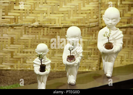 Piccole statue di Buddha holding alberi di bonsai, albero di Bonsai exhibition, Pune Foto Stock