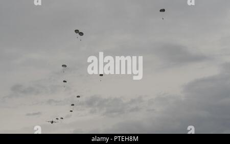 Paracadutisti da più paesi NATO saltare fuori di un U.S. Air Force C-130J Super Hercules durante il salto internazionale settimana, luglio 11, 2017. Oltre 500 membri del servizio sono stati fatti cadere oltre i cinque giorni di formazione e gli organizzatori sono stati in grado di chiudere la settimana senza importanti lesioni. Foto Stock