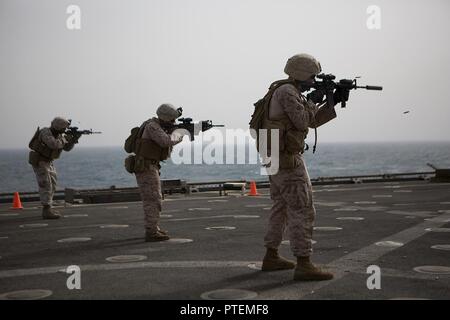 Golfo di Aden (Luglio 16, 2017) DEGLI STATI UNITI Marine Corps Gunnery Sgt. Benito García, sinistra, Sgt. David Piper, centro e Lance Cpl. Nicholas Crider, destra, tutte con 3° Battaglione, 6 Marines fuoco le loro armi sul ponte di volo della USS Carter Hall (LSD 50), il Golfo di Aden, 18 luglio 2017, durante un live fire esercizio. Il ventiquattresimo Marine Expeditionary Unit è attualmente distribuito negli Stati Uniti Quinta Flotta area di operazioni a sostegno della sicurezza marittima operazioni destinate a rassicurare gli alleati e partner e preservare la libertà di navigazione e il libero flusso di commercio nella regione. Foto Stock