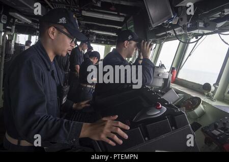 Sul mare del sud della Cina (13 luglio 2017) Ensign Terence Viernes, sinistra, comunica la posizione dei contatti di superficie al pubblico ufficiale di coperta a bordo del Arleigh Burke-class guidato-missile destroyer USS Stethem (DDG 63) durante un transito verso Singapore. Stethem è di pattuglia il supporto di sicurezza e stabilità nella Indo-Asia-regione del Pacifico. Foto Stock