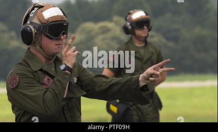 Stati Uniti Marine Corps Lance Cpl. Cody favorisce un meccanico powerline con Marine Fighter Attack Squadron (VMFA) 232, segnali di un F/A-18C Hornet pilota a fuoco i suoi motori al Giappone aria Forza di Autodifesa (JASDF) Hyakuri Air Base, Giappone, luglio 18, 2017. Manutenzione Marines giocare una parte cruciale per i piloti di aeromobili e scendere il terreno in modo sicuro mediante movimentazione del braccio e della mano Segnali per mantenere il livello di consapevolezza della situazione. VMFA-232 è condurre esercitazioni con la JASDF come parte dell'aviazione Formazione Programma di riposizionamento, che è progettata per aumentare la prontezza operativa e interoperabilità tra gli Stati Uniti e il Giappone Foto Stock