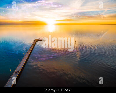 Paesaggio di fantasia - guardare la gente bellissimo tramonto sul mare sul molo con il pianeta e galassia nel cielo che riflette ancora in acqua. Gli elementi di questo im Foto Stock