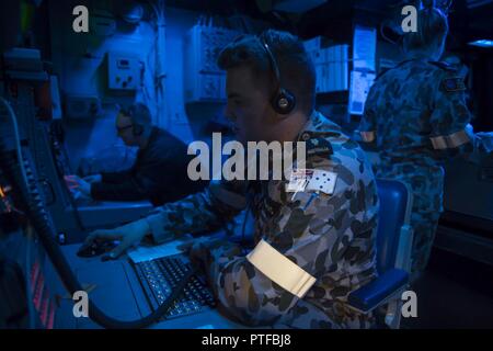 CORAL SEA (Luglio 7, 2017) Royal Australian Navy Sailor in grado marinaio di sistemi di combattimento operatore Samuel Perkins comunica con navi di Stati Uniti-Australia expeditionary strike Group (ESG) da combattimento information center (CIC) a bordo di un assalto anfibio nave USS Bonhomme Richard (LHD 6) durante il talismano di Saber 17. Talismano Saber è una biennale U.S.-australiano esercizio bilaterale tenutosi al largo della costa australiana intende conseguire l'interoperabilità e rafforzare gli Stati Uniti-Australian alliance. Foto Stock