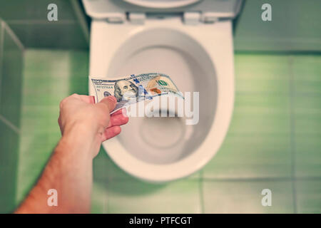 Concetto di assurdo spreco di denaro, perdita inutile spreco, grandi costi di acqua nel wc wash un migliaio di dollari di bill. Foto Stock