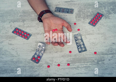 Close up di overdose di pillole e addict sulle mani di uomini, l'uomo suicidarsi da sovradosaggi sul farmaco. compresse di colore rosso nella mano di un giovane Foto Stock