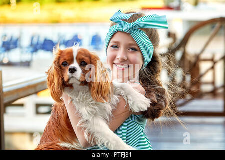 Bambino felice con il cane. Ritratto di close-up di gioia faccia ragazza abbracci cucciolo razza cocker spaniel, Cavalier King Charles. Affascinante pet carino, cane, animale, amicizia con kid. Foto Stock