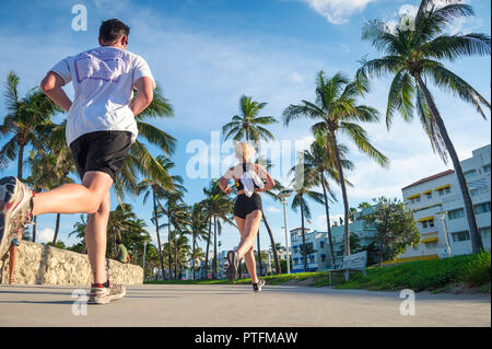 MIAMI - circa agosto, 2018: un giovane uomo e donna corrono insieme contro l'Art Deco skyline di Ocean Drive a South Beach. Foto Stock