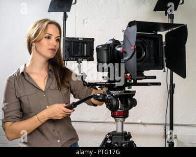 Foto di una donna operando una fotocamera DSLR rig per riprese video. Foto Stock